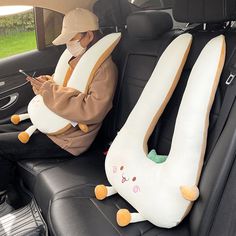 a person sitting in the back seat of a car with two stuffed animals on it