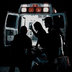 three people standing in front of an ambulance