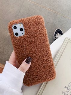 a woman is holding up her phone case to show it's fuzzy fabric design