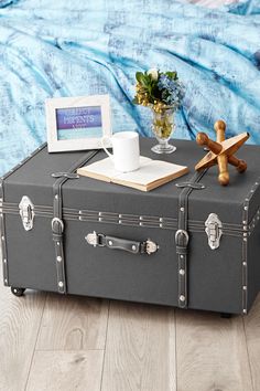 an old suitcase is sitting on the floor next to a vase with flowers and a cross