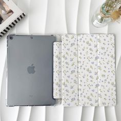 an ipad case sitting on top of a white table next to a vase with flowers