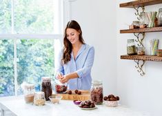 a woman standing in front of a kitchen counter filled with jars and food on top of it