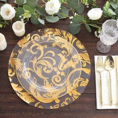 the table is set with gold and black plates, silverware, and white flowers