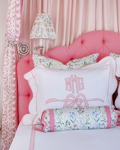 a bed with pink headboard and pillows on it