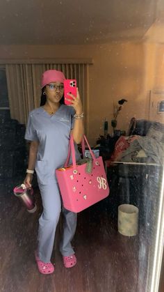 a woman in scrubs is taking a selfie with her cell phone and pink purse