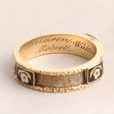 ((about))This very special, utterly heartbreaking Victorian mourning ring was commissioned by a mother who outlived her five children. Fashioned in 18k gold, the ring features a hair locket at the face and three interstitial enamel forget me not panels that divide the channel of the hoop into four sections, each of which is inlaid with the hair of a unique individual. The interior is engraved: "In memory of my dear children Walter Janet Jane Jessie Robert." "Hair is at once the most delicate and Lovket Ring, Victorian Style Etched Ring Jewelry, Victorian Engraved Memorial Rings, Victorian Etched Ring Jewelry, Victorian Gold Jewelry For Memorial, Victorian Hair Jewelry Memento Mori, Hair Locket, Victorian Hair, Locket Ring