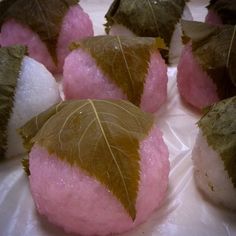 several leaf shaped desserts are displayed on a white plate with pink and green frosting