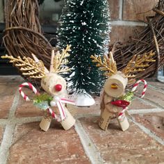 two wooden reindeer figurines sitting next to a christmas tree