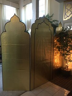 three metal screens in the middle of a room with a potted plant next to them