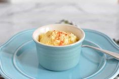 a bowl of food on a blue plate with a spoon and napkin next to it