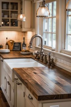 a kitchen with white cabinets and wooden counter tops, along with two hanging lights over the sink