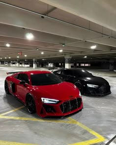 two red and black sports cars parked in a parking garage with yellow lines painted on the floor