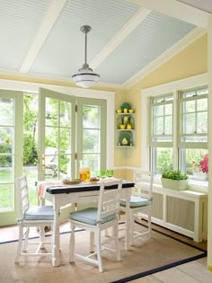 a dining room with yellow walls and white furniture, along with windows that look out onto the yard