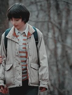 a boy with a backpack walking in the woods