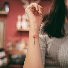 a woman's arm with a small flower tattoo on it