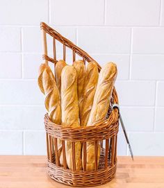 a basket filled with loaves of bread on top of a wooden table next to a knife