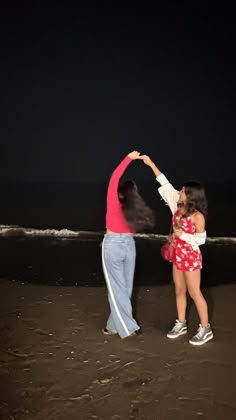 two people are dancing on the beach at night