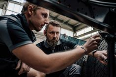 two men working on a tire in a factory or repair shop, one is fixing the tire