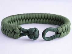 a close up of a green rope bracelet on a white surface with an object in the background