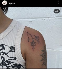 a woman with a tattoo on her arm and shoulder is standing in front of a white brick wall