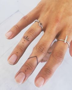 a person's hand with two rings on it and a cross tattooed on the middle finger