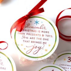 christmas tags with red ribbon tied around them on top of a table next to candy