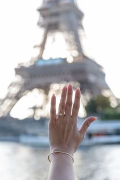 a woman's hand reaching up towards the eiffel tower in paris, france