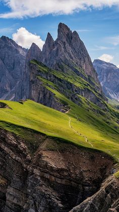 the mountains are covered in green grass and there is a trail going through them that goes up to the top