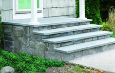 a house with steps leading up to the front door and green doors on each side