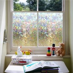 an open book sitting on top of a window sill next to a stuffed animal