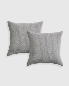 two grey pillows with cable knits on the front and back, one is made out of