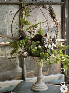 a vase filled with flowers and greenery on top of a table