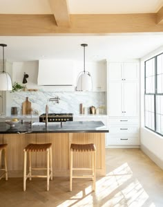 a kitchen with two stools in front of an island and marble counter tops on the wall