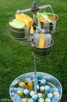 a metal bucket filled with drinks on top of a grass covered field