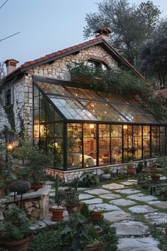 a glass house with lots of plants in the front yard and walkway leading up to it