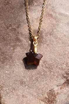 Necklace composed of a 1.2 cm faceted star-shaped tiger's eye stone and a 45 cm gold-colored stainless steel chain.