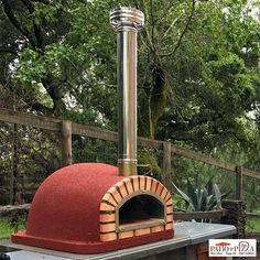 an outdoor brick pizza oven with a red cover on it's roof and chimney