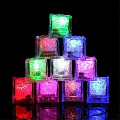 many different colored ice cubes sitting on top of each other in front of a black background