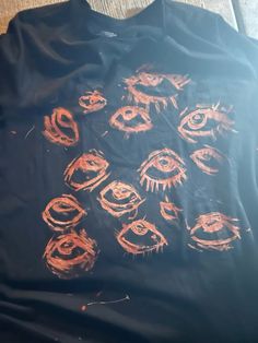 an orange drawing on a black t - shirt that has eyes drawn on the front