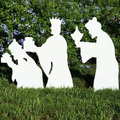 three silhouettes of people in the grass with trees and bushes behind them, one is holding