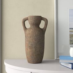 a brown vase sitting on top of a white shelf