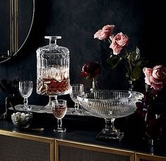 a table topped with glass dishes and vases filled with flowers next to a mirror