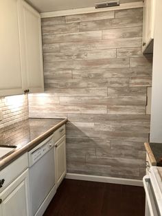 an empty kitchen with white cabinets and wood flooring on the wall behind the stove