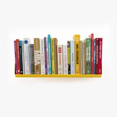 a yellow book shelf filled with books on top of each other and several different colored books