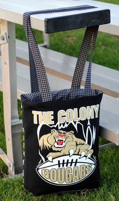 a black tote bag sitting on top of a wooden bench