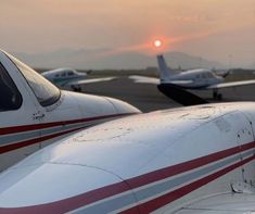 the sun is setting behind two airplanes on the tarmac