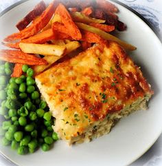 a white plate topped with meat and vegetables next to french fries, peas and carrots