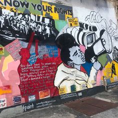 a wall covered in lots of graffiti and writing on it's sides, including a man holding a camera