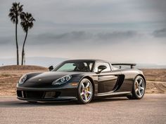 a black sports car is parked on the side of the road in front of palm trees