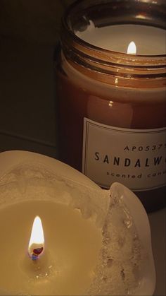 a candle that is sitting next to a glass jar with some liquid in it on a table